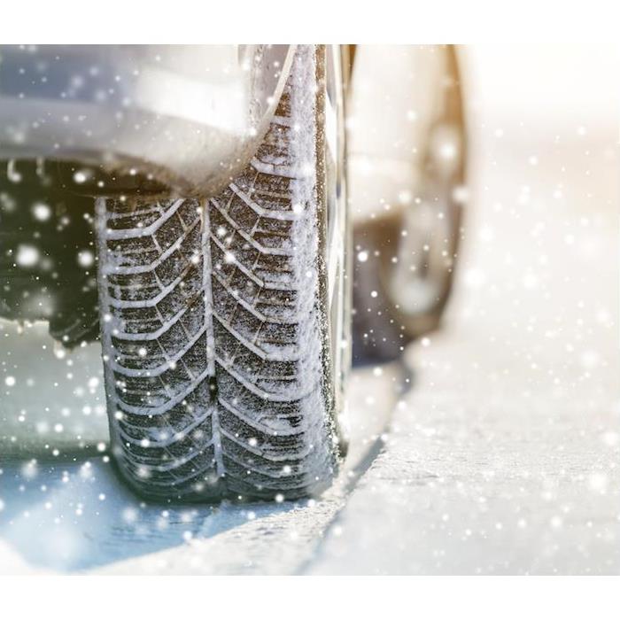 a close-up image of a car and tire moving through snow 